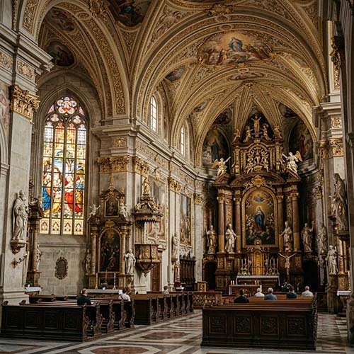 Interior de una iglesia de piedra con luz cálida entrando por un vitral